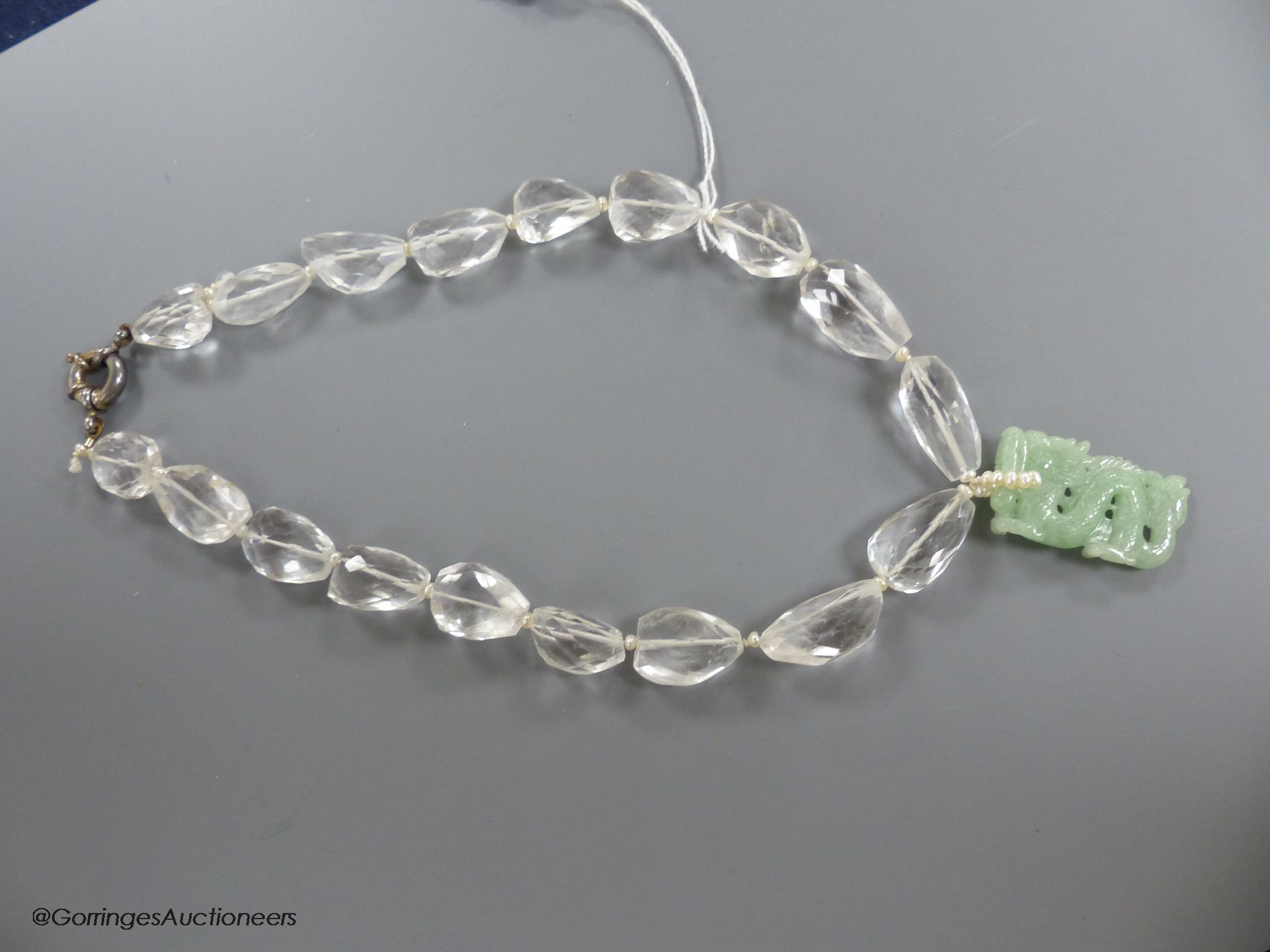 A shaped facet cut rock crystal necklace, with carved jade pendant, seed pearl bale and white metal clasp, necklace approx. 43cm, pendant 36mm, gross weight 97 grams.